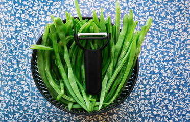 Flat runner bean pods, green beans with vegetable peeler on middle,sliced to cook with olive oil and onion , Mediterranean cuisine ,'Çalı Fasulyesi ' in Turkish.