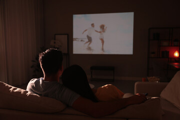 Couple watching movie on sofa at night, back view