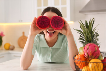 Young woman with fresh pitahaya in kitchen. Exotic fruit