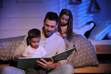 Father reading bedtime story to his children at home