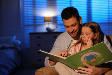 Father reading bedtime story to his daughter at home