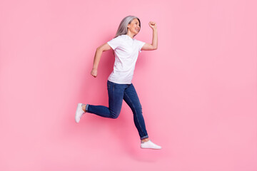 Fototapeta na wymiar Photo of sweet hurrying mature lady wear white clothes humping high running fast smiling isolated pink color background