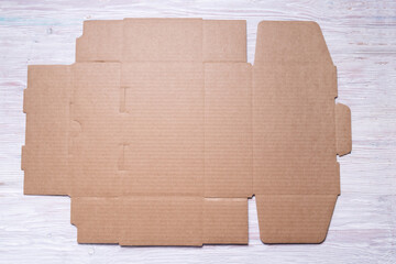 Flat unfolded brown cardboard box on wooden background