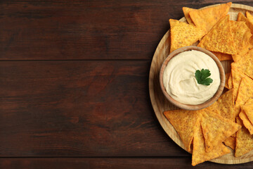 Delicious hummus with nachos on wooden table, top view. Space for text