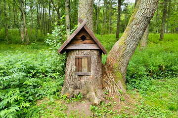 Wooden bird house feeder in garden park with green tree background