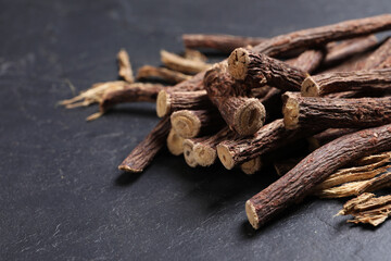 Dried sticks of liquorice root on black table, closeup. Space for text