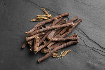 Dried sticks of liquorice root on black table, flat lay