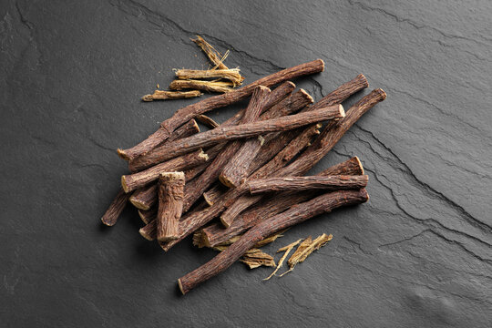 Dried sticks of liquorice root on black table, flat lay