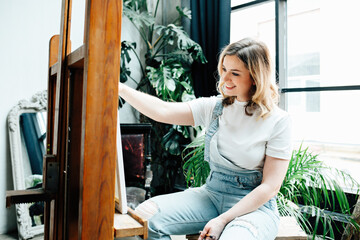 Young woman draws in a light studio, self-development and hobbies