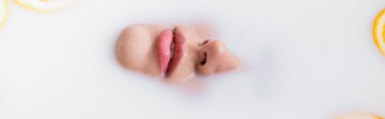top view of female face immersed in milk bath, banner.