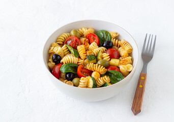 Pasta salad with tomatoes, zucchini, olives and spinach. Healthy eating. Vegetarian food.