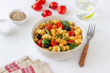 Pasta salad with tomatoes, zucchini, olives and spinach. Healthy eating. Vegetarian food.