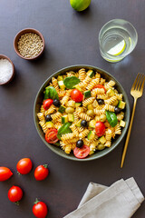 Pasta salad with tomatoes, zucchini, olives and spinach. Healthy eating. Vegetarian food.
