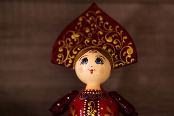 A traditional Russian Matryoshka, wooden nesting doll with kokoshnik and beautiful face, in gold, yellow, red colors. Close-up.