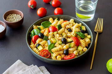 Pasta salad with tomatoes, zucchini, olives and spinach. Healthy eating. Vegetarian food.