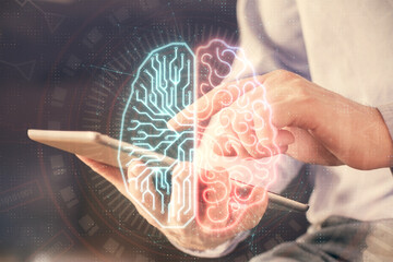 Double exposure of man's hand holding and using a digital device and brain hologram drawing. Data...