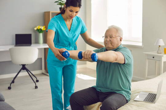 Physician, Physiotherapist Or Home Care Nurse Checks How Happy Old Male Patient Does Arm Exercise During Wellness Workout Practice. Providing Help, Physical Therapy And Senior Citizens Rehabilitation