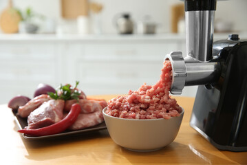 Modern meat grinder and products on wooden table in kitchen