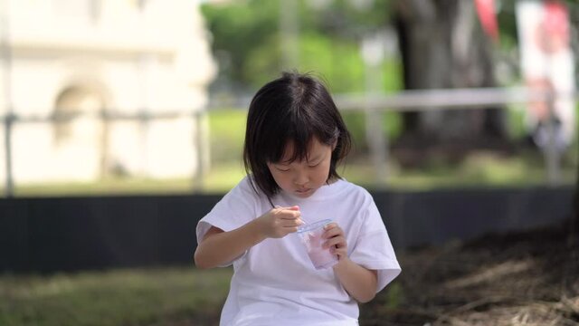 Asian chinese child girl eating ice cream hungrily for the first time