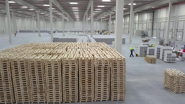 air flight over a pile of stacked pallets in a logistics warehouse