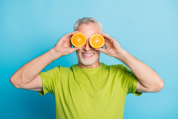 Portrait of attractive cheerful grey-haired man closing eyes with orange pieces isolated over...