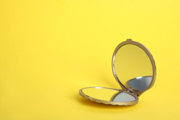 Stylish cosmetic pocket mirror on yellow background, space for text