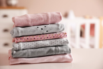 Stack of clean girl's clothes on table indoors