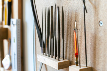 Group of fine metal rasps set in wooden holder in the luthier's workshop