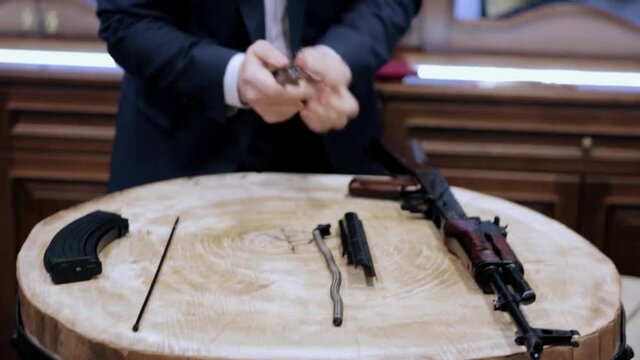 Process of assembly of the Kalashnikov rifle. Video. Close up of man dressed in official suit assembling the automatic gun during special event.