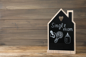Chalkboard with words Single Mom and baby accessories on wooden table. Space for text