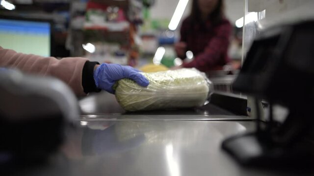 Women's hands in gloves accept the goods. Cashier in the store. Paying for food in the supermarket.
