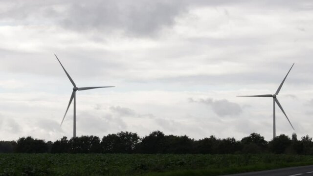 wind turbines in France next to a highway in a closer look, in a cloudy day