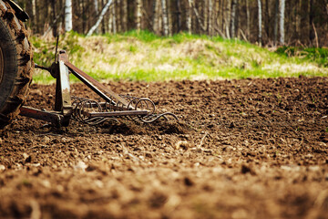 plow tractor plows the land for planting agricultural plants. the farmer cultivates the land in the spring for sowing seeds. iron plow of the mechanized machine