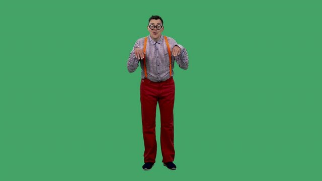 Portrait of a man looking at the camera and depicting an animal, a dog. A man in glasses, a plaid shirt with orange suspenders in the studio on a green screen. Slow motion.