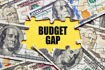 The word budget gap surrounded by puzzle pieces with dollar bill money. Business finance