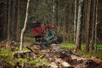a crawler tractor is driving through a forest clearing. an industrial bulldozer is stuck in the mud. trucks are skidding in the ground