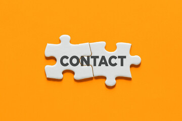 Two puzzle pieces connected with the word contact. Communication, cooperation or interaction concept.