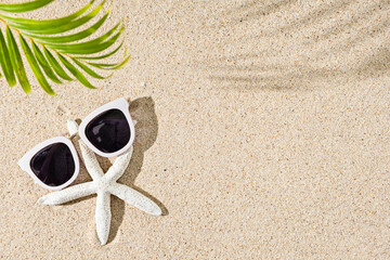 Fototapeta na wymiar White Starfish and white sunglasses on natural sand background, copy space, shadows