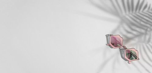 Funky sunglasses in pink lips shape on gray background with tropical shades, copy space,banner