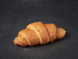 baked french croissants on a brown kitchen board, black background, close-up