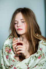 Young beautiful white woman awaking in light room. Relaxed woman lying in bed and drink tea. Good morning concept. Russian girl.