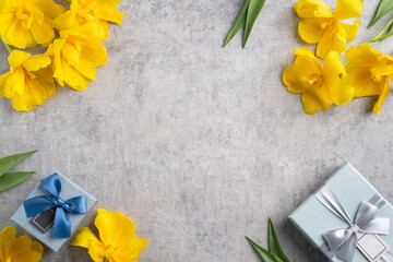 Mother's day background. Top view of gift with yellow tulip bouquet on gray table background