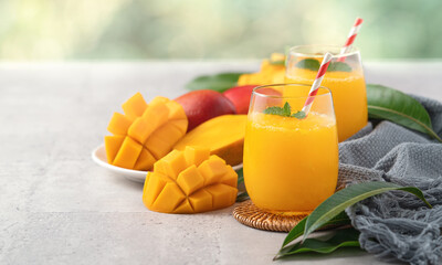 Fresh beautiful delicious mango juice smoothie in a glass cup on gray table background.