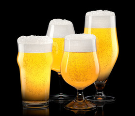 Set of fresh light beer glasses with bubble froth isolated on black background.