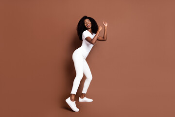 Fototapeta na wymiar Full body portrait of charming dark skin girl closed eyes partying have good mood isolated on brown color background