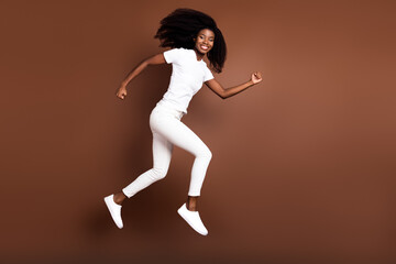 Fototapeta na wymiar Full length body size view of attractive cheerful energetic girl jumping running isolated over brown color background