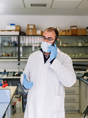 doctor talking on his cell phone in the lab. chemist technician using his cell phone. vertical photograph.