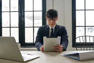 Asian manager businessman use tablet in on working desk in home office