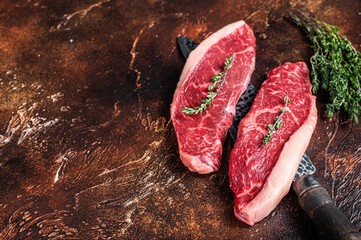 Uncooked Raw top sirloin cap or rump beef meat steaks on a butcher knife. Dark background. Top view. Copy space