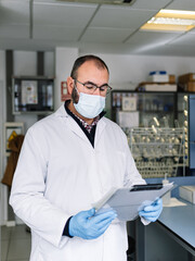 Fototapeta na wymiar chemist reviewing a work report. Lab technician with protective mask looking at technical data. photography vertical
